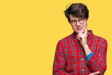 Young handsome man wearing glasses over isolated background with hand on chin thinking about question, pensive expression. Smiling with thoughtful face. Doubt concept.