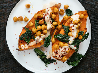 Baked sweet potatoes loaded with spicy chickpeas and kale and a tahini Dressing