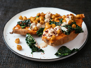 Baked sweet potatoes loaded with spicy chickpeas and kale and a tahini Dressing