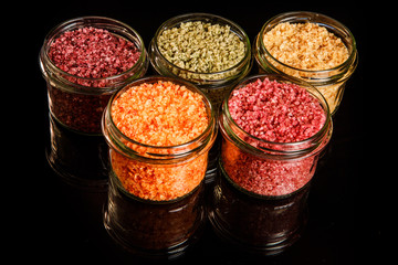 top view of small glass jars filled with different colors sea salt