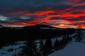 Magnificent landscape of the Carpathian Mountains at dawn with bright red clouds