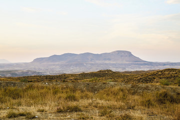 mountains at horizon in the fog with a steppe grassland landscape in the foreground