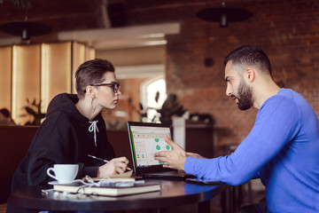 Cheerful caucasian woman and multicultural man enjoying learning together at cafe