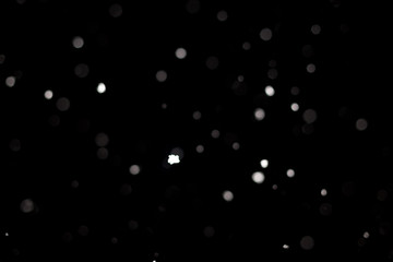 Snowstorm texture. Bokeh lights on black background, shot of flying snowflakes in the air