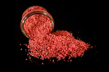 big pink organic sea salt poured out from small glass jar