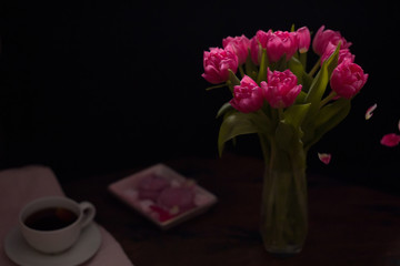Still life of pink tulip flowers in vase on dark background