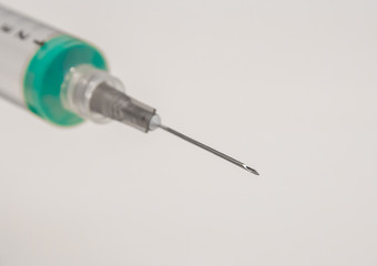 macro photo of a syringe with needle and a liquid inside, in close up.
