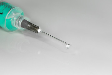 macro photo of a syringe with needle and a liquid inside, in close up.