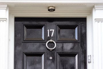 House number seventeen in silver numerals on a black wooden door with silver knocker, 17
