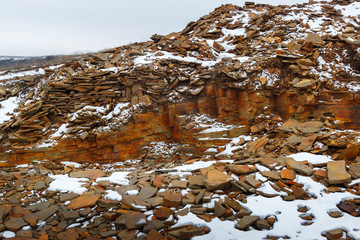 Heaps of the decorative rock in the opencast quarry at the winter snowy time