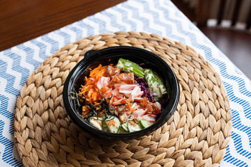 hawaii poke bowl with salmon, rice, surimi, avocado, tobiko, carrot and seaweed