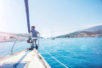 Little boy on board of sailing yacht on summer cruise. Travel adventure, yachting with child on family vacation.