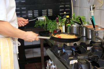 Kucharz w restauracji podgrzewa spaghetti na patelni w kuchni. - obrazy, fototapety, plakaty
