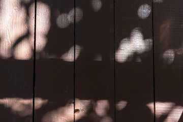 The wooden floor of the rough boards, painted with brown paint. Lots of sunshine and shadows. Textured.