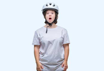 Young adult cyclist woman with down syndrome wearing safety helmet over isolated background afraid and shocked with surprise expression, fear and excited face.