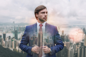 Great style! Handsome young businessman adjusting his jacket and looking away while standing...