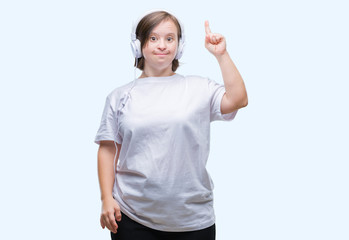 Young adult woman with down syndrome wearing headphones over isolated background pointing finger up...