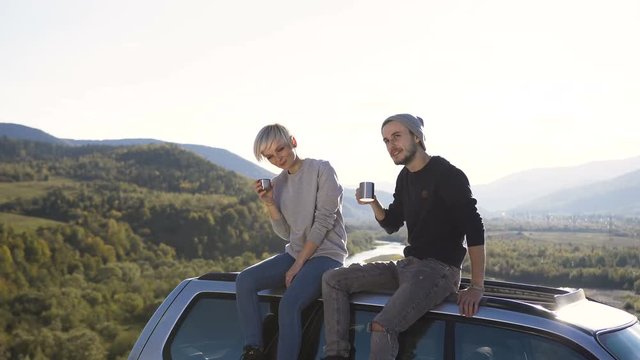 Dolly shot of cute hipster drinking tea while relaxing in the mountain.