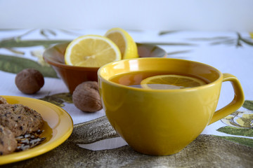  A cup of green tea with lemon, biscuits with flax and sesame seeds, sliced lemon, whole walnuts. Close up. The concept of healthy eating.