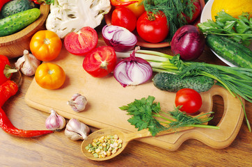 Vegetables on the kitchen board. Tomatoes, cucumbers, onions, garlic, pepper, parsley.
