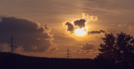 Obraz premium sunset with electricity tower in countryside. Summer scene. Dusk sky with sun. Spring sunset