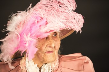 Old stylish lady in mauve jacket and a hat