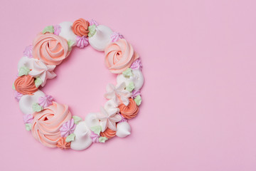 Obraz na płótnie Canvas wreath of colored meringues on a pink pastel background, the concept of summer and holiday