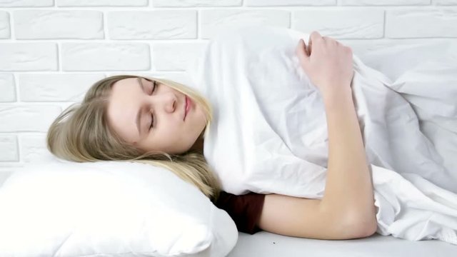 Young woman sleeping in bed and waking up in the morning