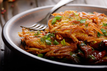 Closeup view at Homemade tasty potato pancakes in clay dish with sun-dried tomatoes