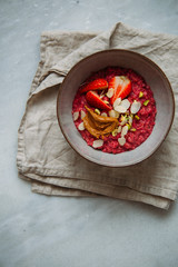 Oatmeal porridge with strawberries and fruit yogurt and pistachios, peanut butter and almond in bowl. Morning concept with copy space