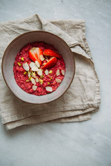 Oatmeal porridge with strawberries and fruit yogurt and pistachios, peanut butter and almond in bowl. Morning concept with copy space