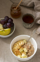 Buckwheat porridge with fruit, green tea, fruit and honey on a linen tablecloth. Rustic style.