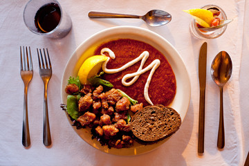 A top down view of a stylized plate of food is adorned with a cursive 'M' 