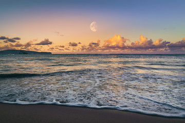 Beautiful sunset on tropical beach with orange clouds white moon and purple sky in Dominican Republic