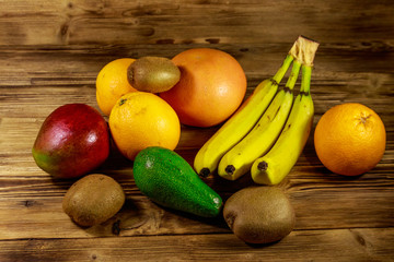 Assortment of tropical fruits on wooden table. Still life with bananas, mango, oranges, avocado, grapefruit and kiwi fruits
