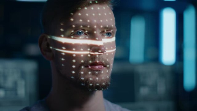 Handsome Young Caucasian Man is Identified by Biometric Facial Recognition Scanning Process. Futuristic Concept: Projector Identifies Individual by Illuminating Face by Dots and Scanning with Laser