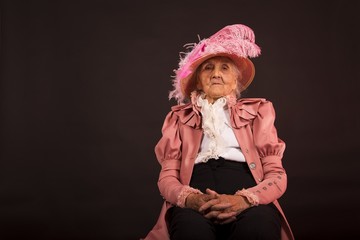 Old stylish lady in mauve jacket and a hat