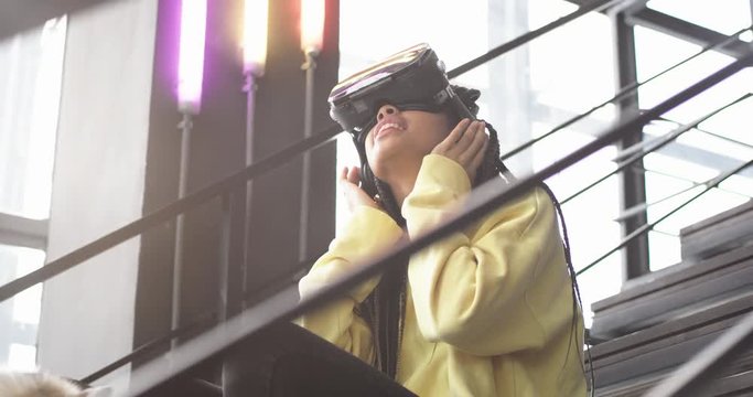 Young african lady with her husky dog on the stairs in the modern office building, woman exploring the VR glasses she are very curiously looking around