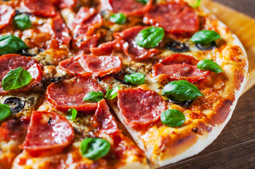 Pepperoni Pizza with Mozzarella cheese, salami, Tomatoes, olive, pepper, Spices and Fresh Basil. Italian pizza on wooden table background