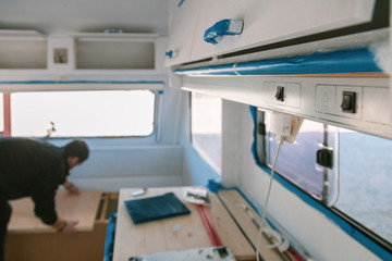 Young man restoring his old caravan from inside