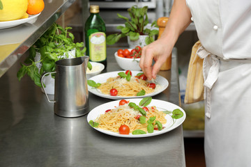 Kucharz przygotowuje spaghetti na białych talerzach. - obrazy, fototapety, plakaty