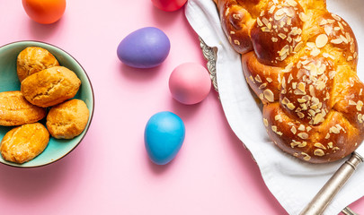 Easter eggs and tsoureki braid, greek easter sweet bread, on pink color background
