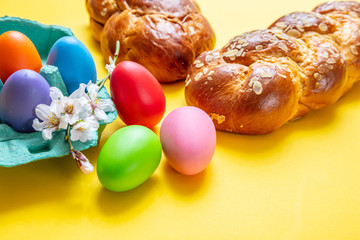 Easter eggs and tsoureki braid, greek easter sweet bread, on yellow background