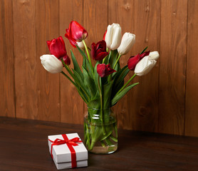 tulip flowers are in a vase, wooden background