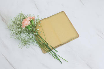 top view vintage book with empty sheets and flowers on a marble background