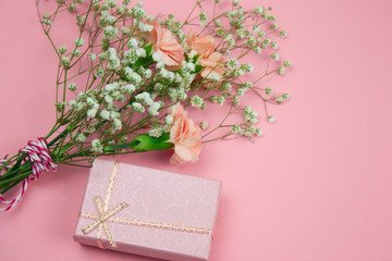 top view pink gift box and flowers on a pastel pink background