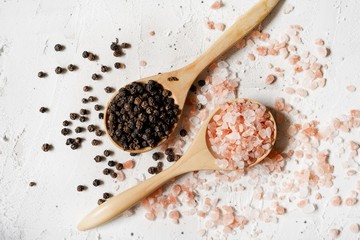 Salt and pepper in a wooden spoon, selective focus