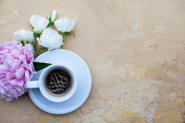 White cup of coffee with pink bud on beigebackground