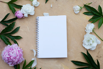Open notebook with flowers and black coffee on beige background. Flat lay. Top view. Copy space.
