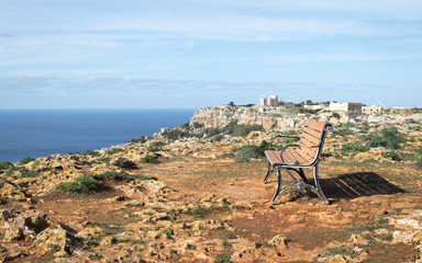 Fototapeta na wymiar A beautiful bench seat invite you to relax on a silent, sunny and clear day in your vacation. Nice place on Dingli Cliffs with a view on the Sea and the horizon. Dingli, Malta, Europe.